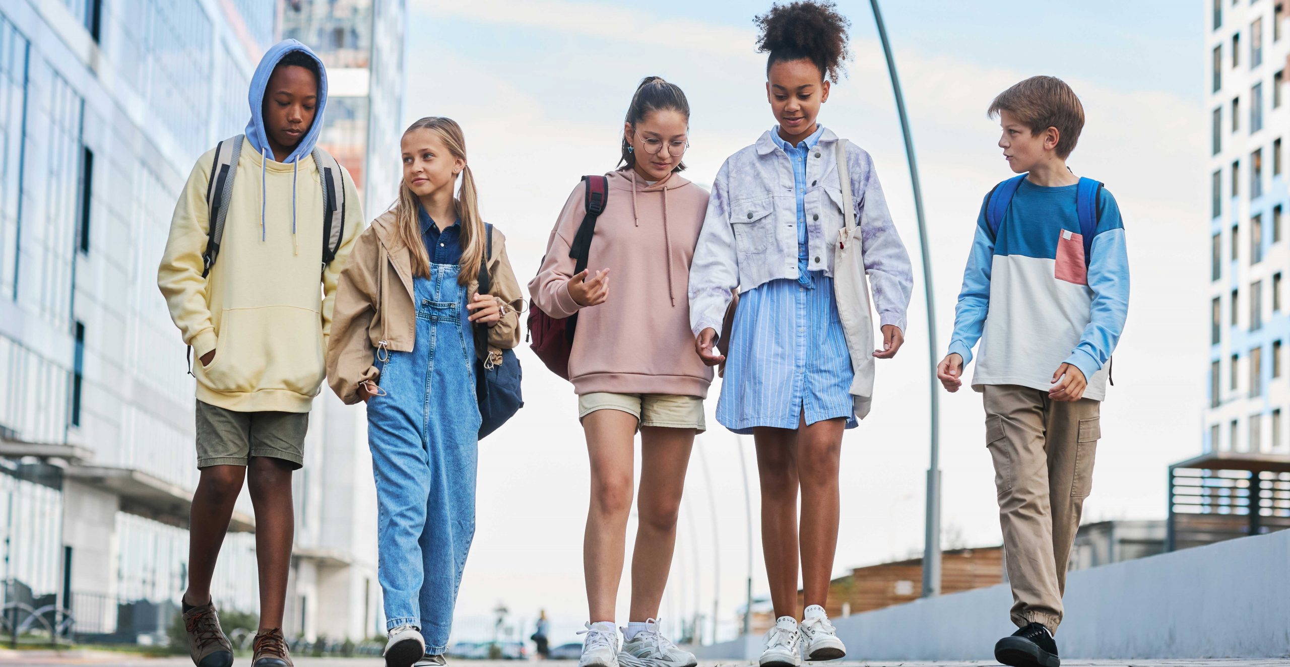 Group of five young teenagers walking side by side